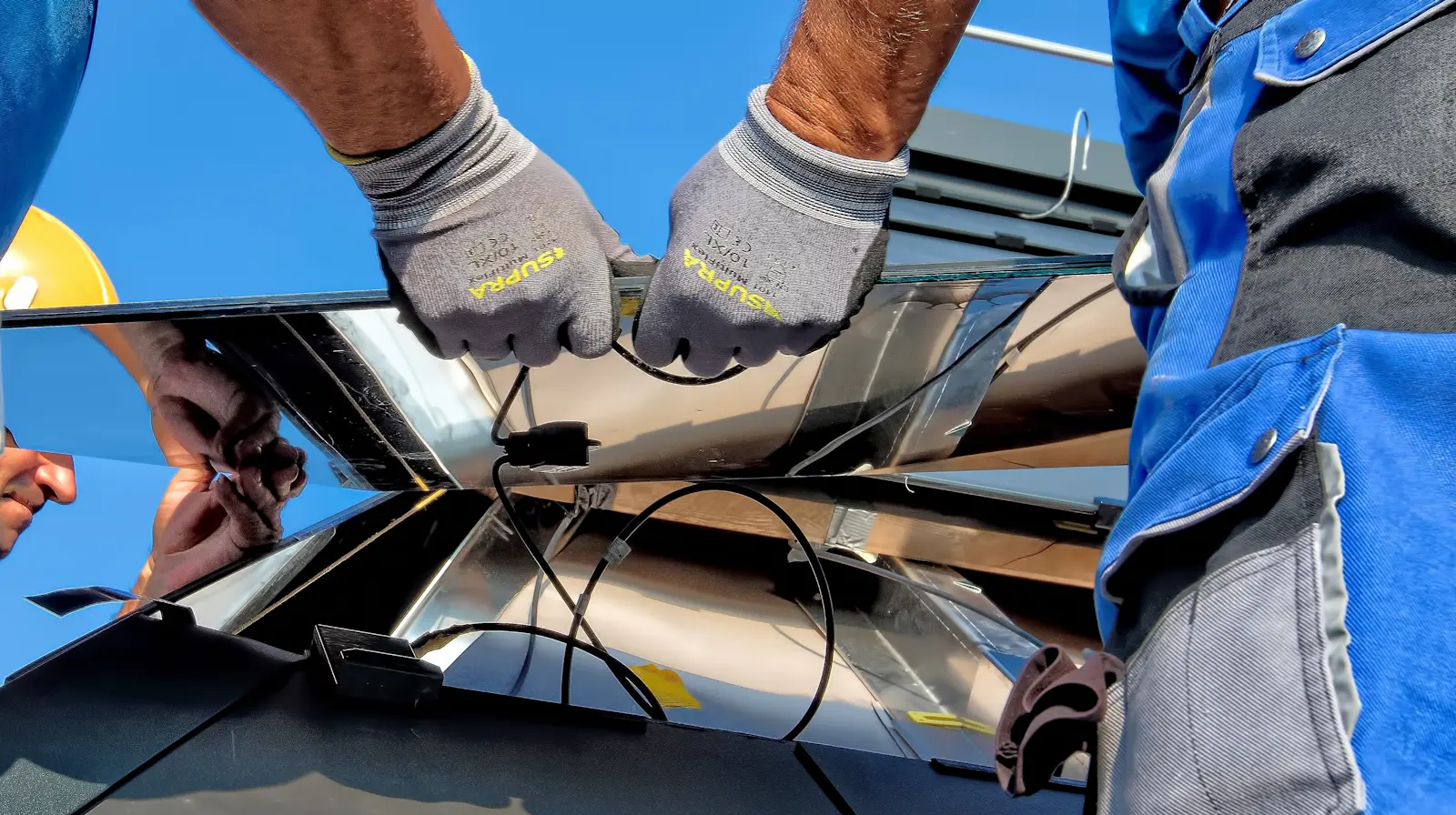 Mãos com luvas encaixando um módulo fotovoltaico na estrutura de fixação