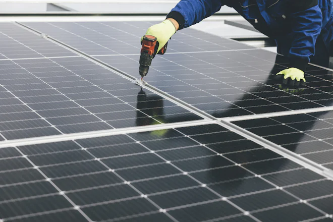 Técnico usando parafusadeira para fixar um módulo fotovoltaico