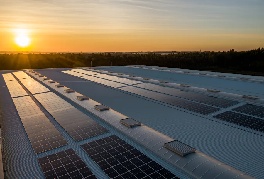 Sistema fotovoltaico ocupando o telhado metálico de um galpão industrial ao pôr do sol